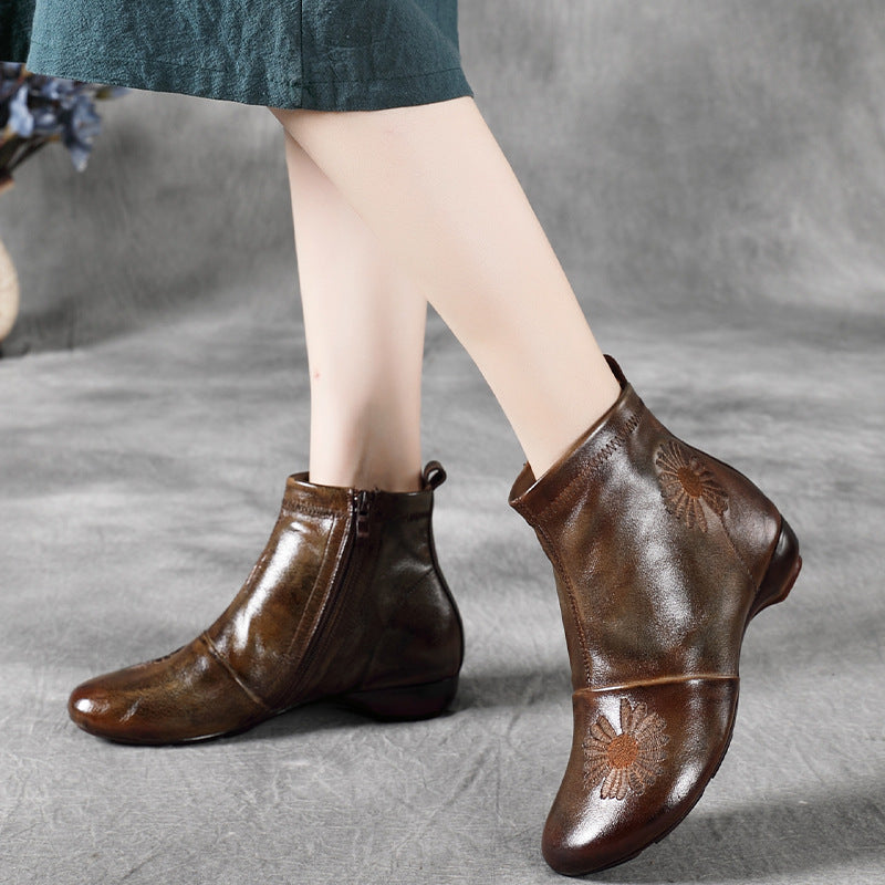 Brown leather ankle boots with floral embroidery on a gray background