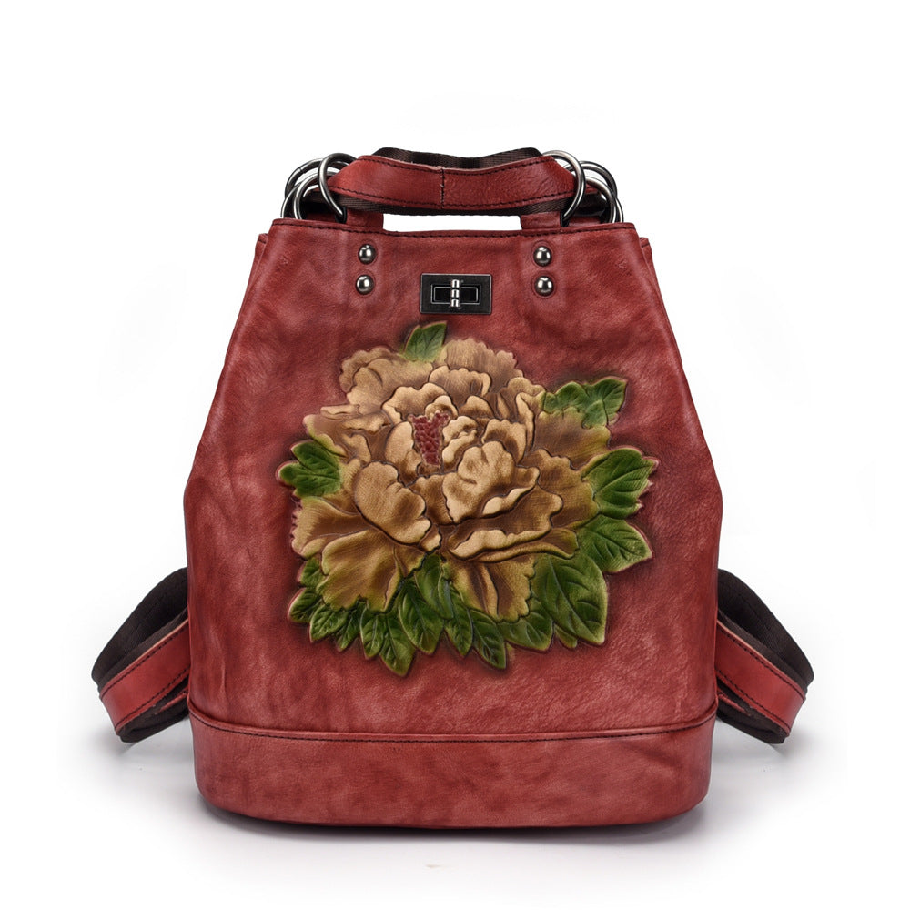 Red leather handbag with a floral design on a white background