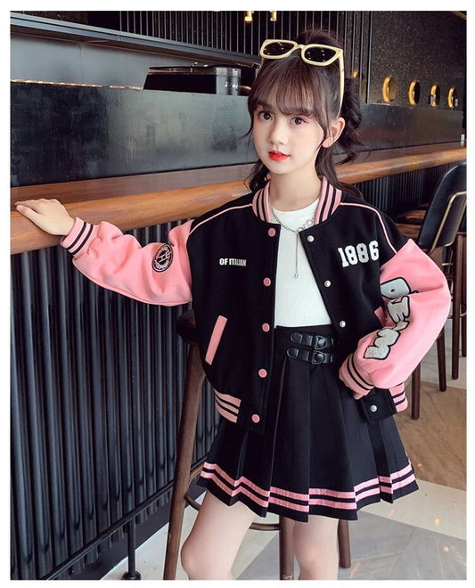Person wearing a black and pink varsity jacket with a white shirt and black skirt in an indoor setting.