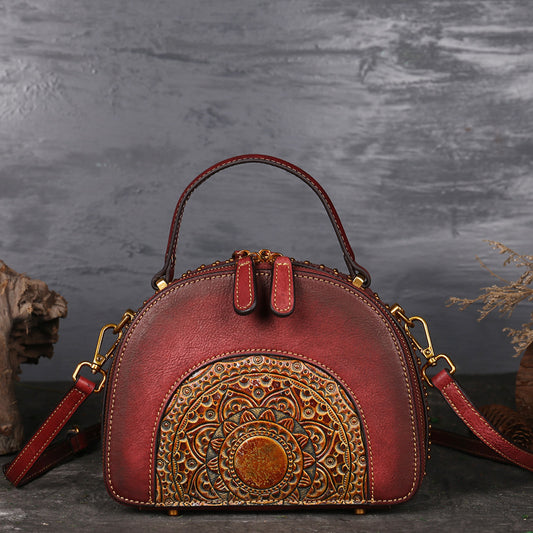 Red handbag with intricate gold patterns on a dark background
