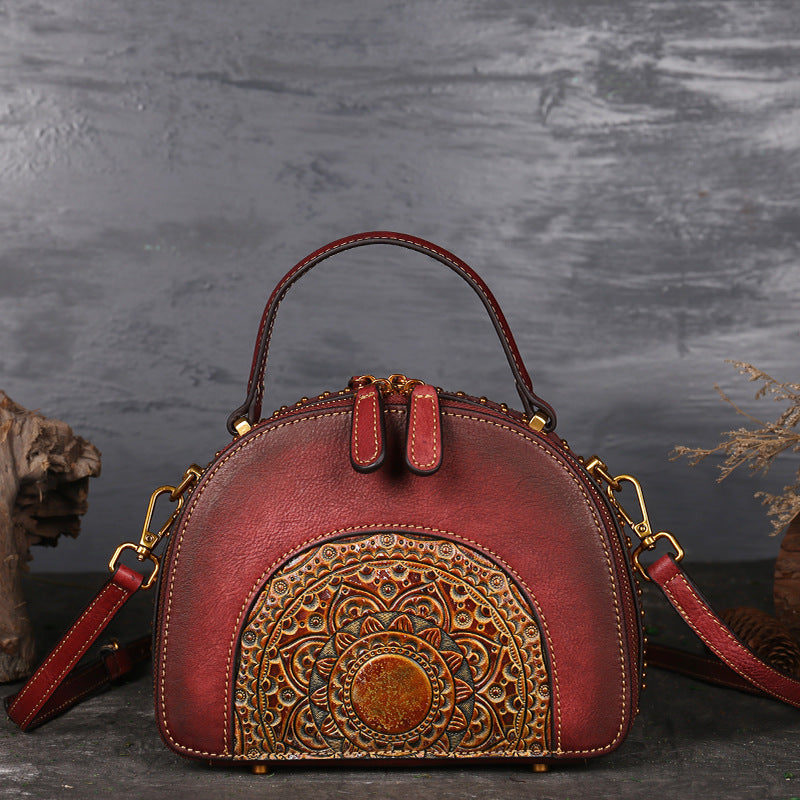 Red handbag with intricate gold patterns on a dark background