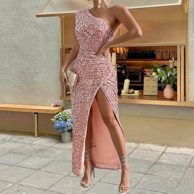 Woman in a pink sequin dress with a high slit standing outdoors.