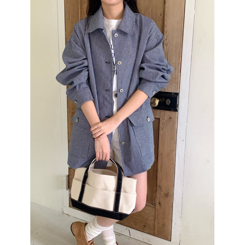 Person wearing a blue checkered shirt holding a white handbag with black accents.