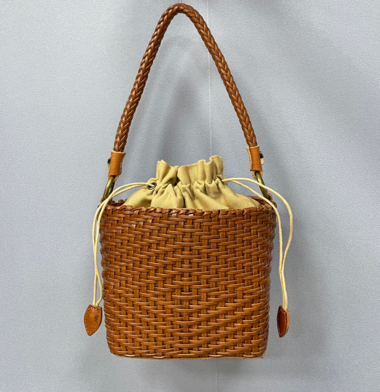 Brown woven bucket bag with a drawstring on a gray background