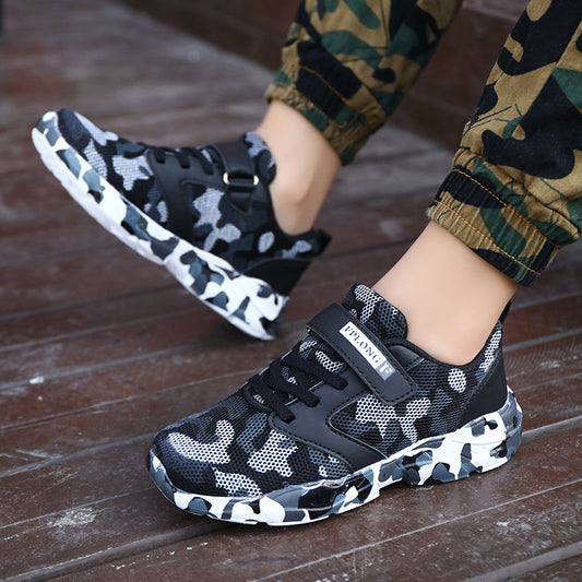 Black and white camouflage sneakers worn by a child on a wooden floor.