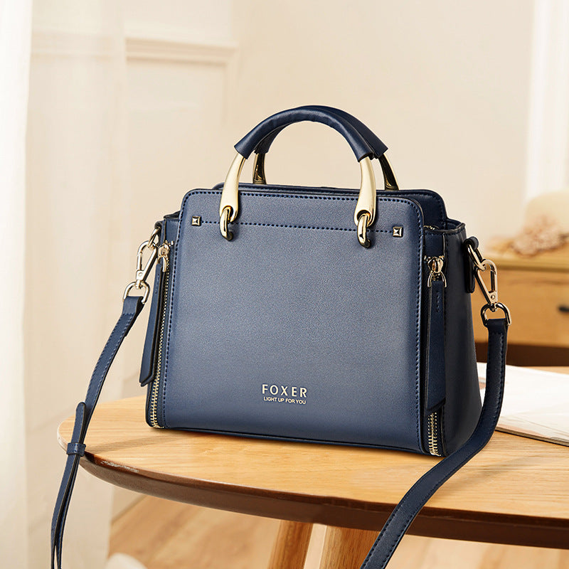 Blue handbag with gold accents on a wooden table