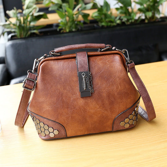 Brown leather handbag with hexagonal patterns on a wooden surface