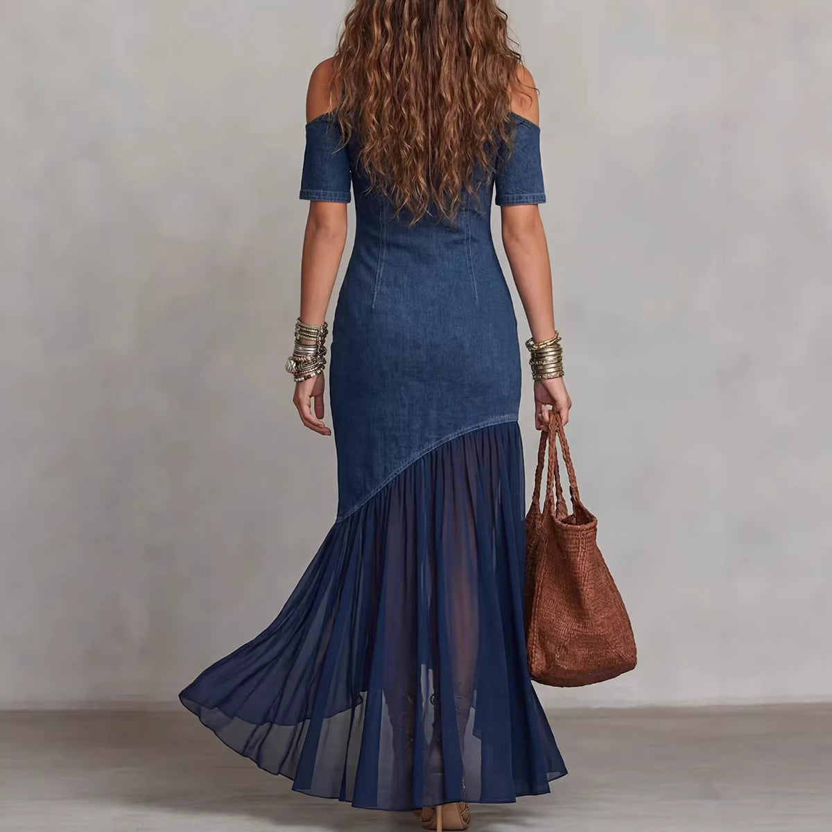Woman wearing a blue dress with a brown handbag against a plain background by millivan