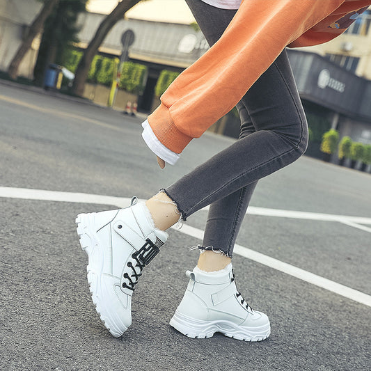 White high-top sneakers worn on a street with a blurred background