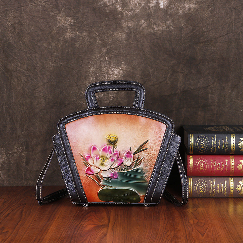 Handbag with floral design next to books on a wooden surface