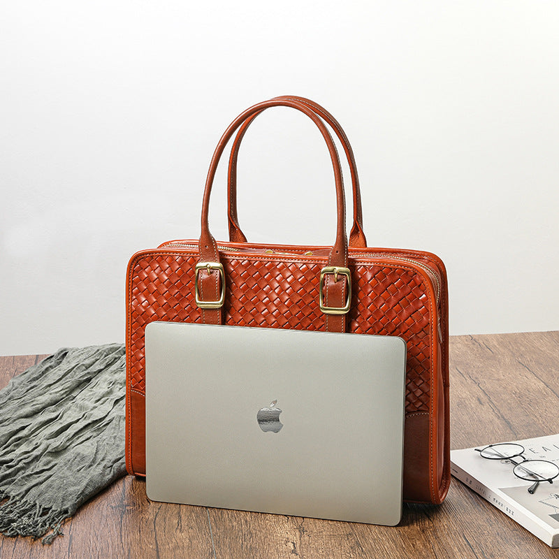 Brown woven handbag with a silver laptop on a wooden surface