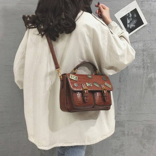 Person wearing a white coat with a brown leather satchel bag on a gray background