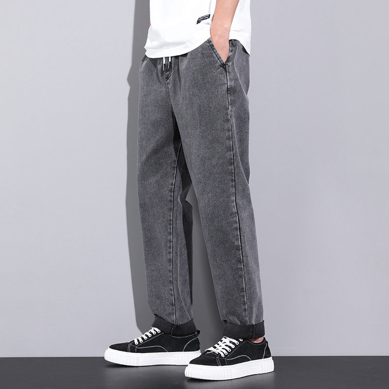 Person wearing gray jeans and black sneakers on a plain background