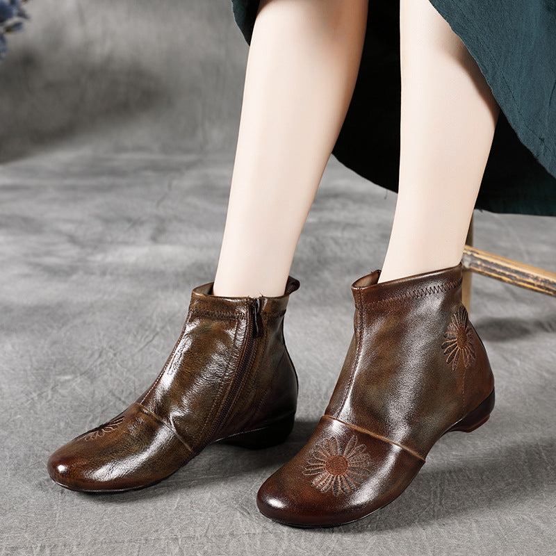 Brown leather ankle boots with floral embroidery on a gray surface
