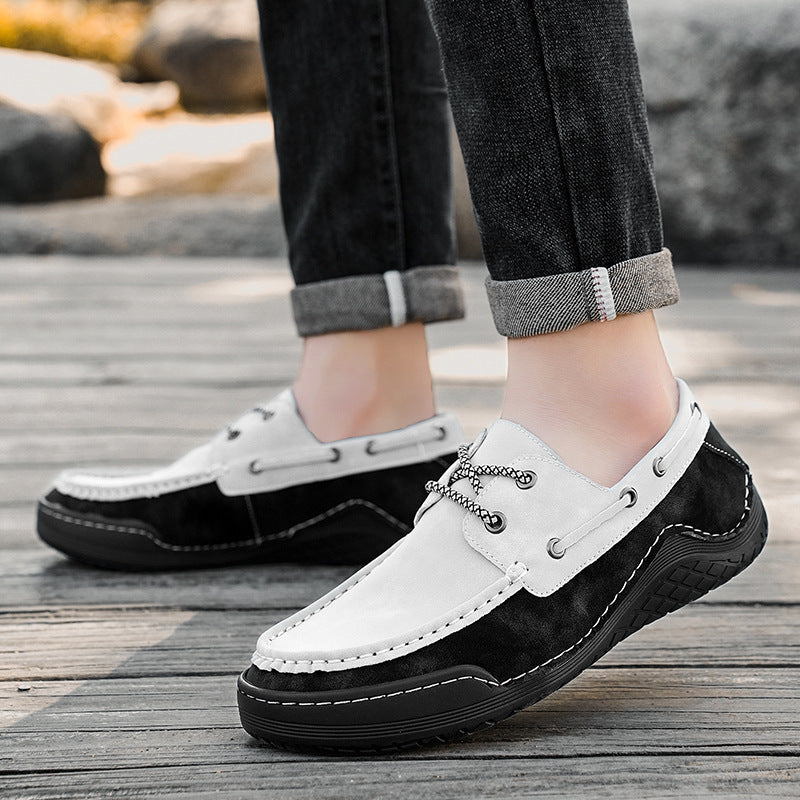 White and black loafers worn by a person on a wooden floor.