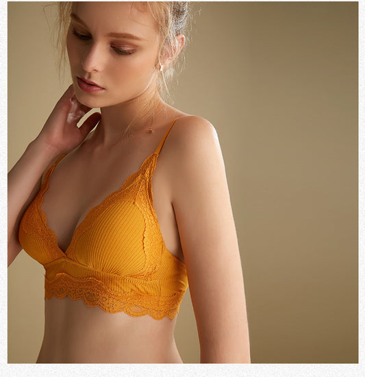 Woman wearing a yellow lace bralette against a beige background
