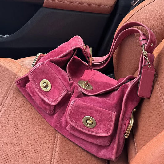 Pink handbag with gold accents on a car seat