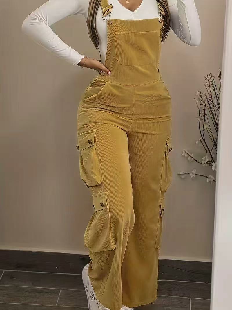 Person wearing mustard yellow corduroy overalls with a plain background