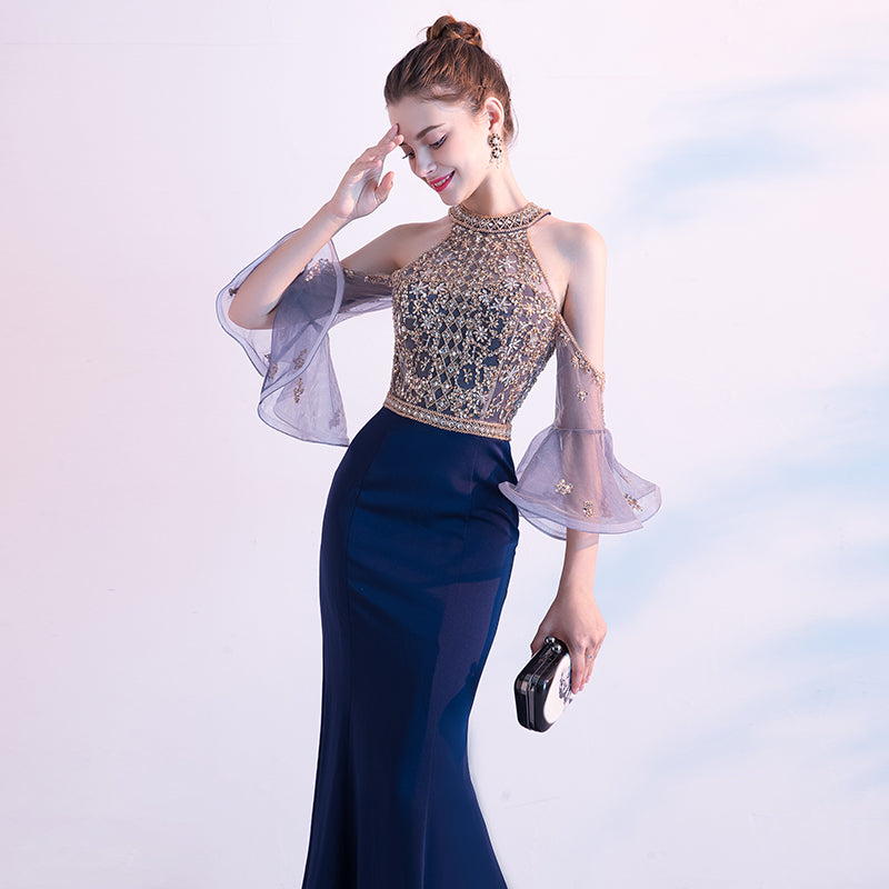 Woman in a formal gown with sheer sleeves against a light background