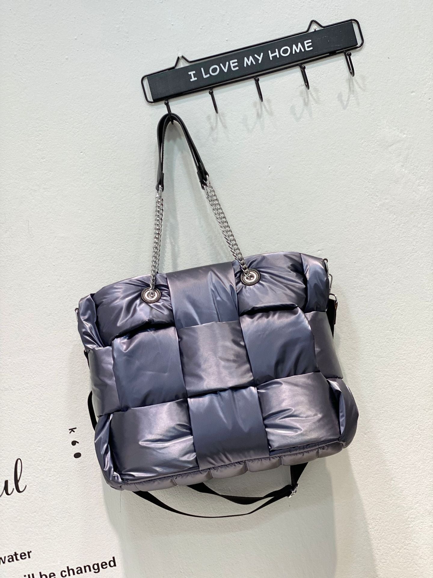 Puffer bag hanging on a hook with 'I Love My Home' sign in the background