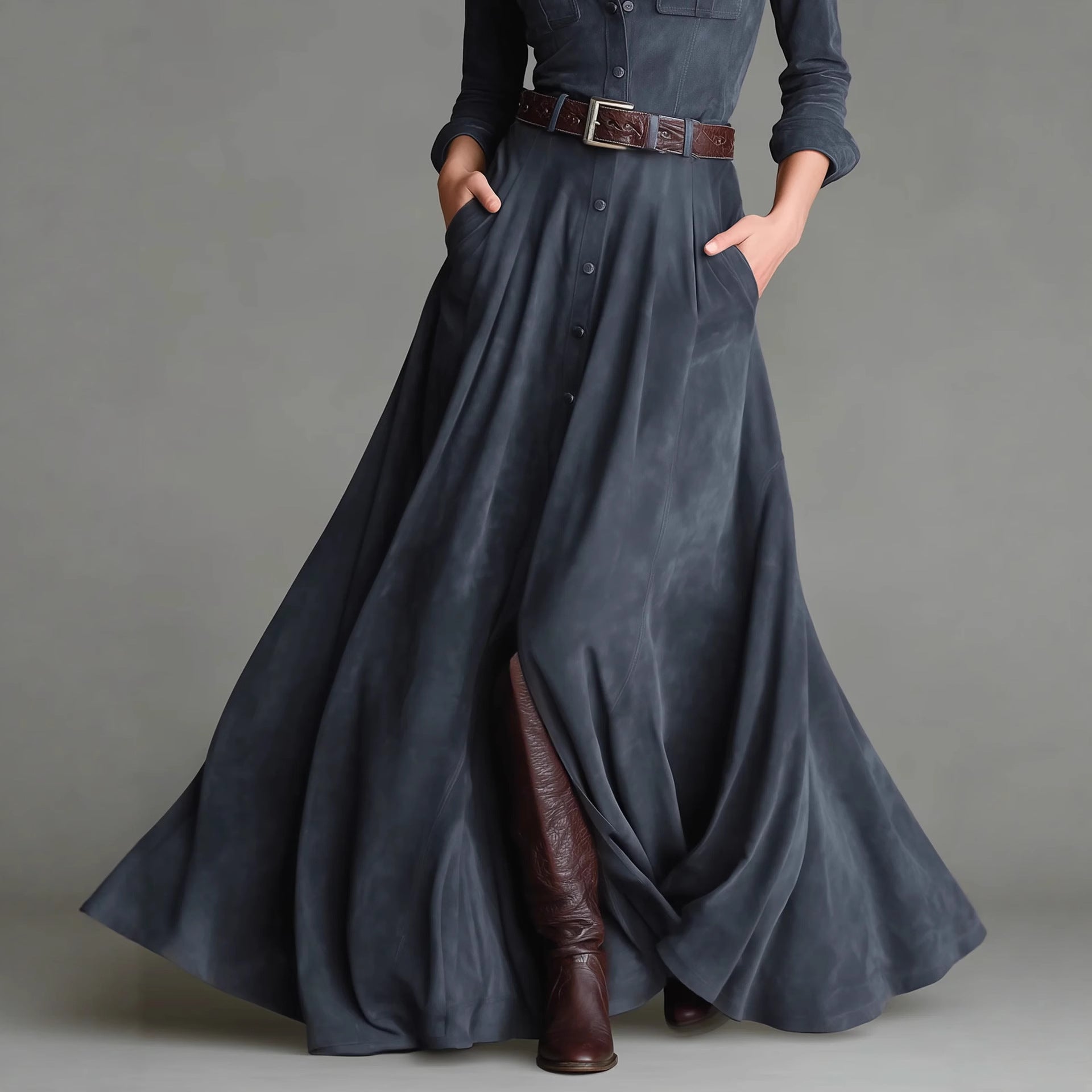 Person wearing a long dark blue dress with brown boots on a gray background