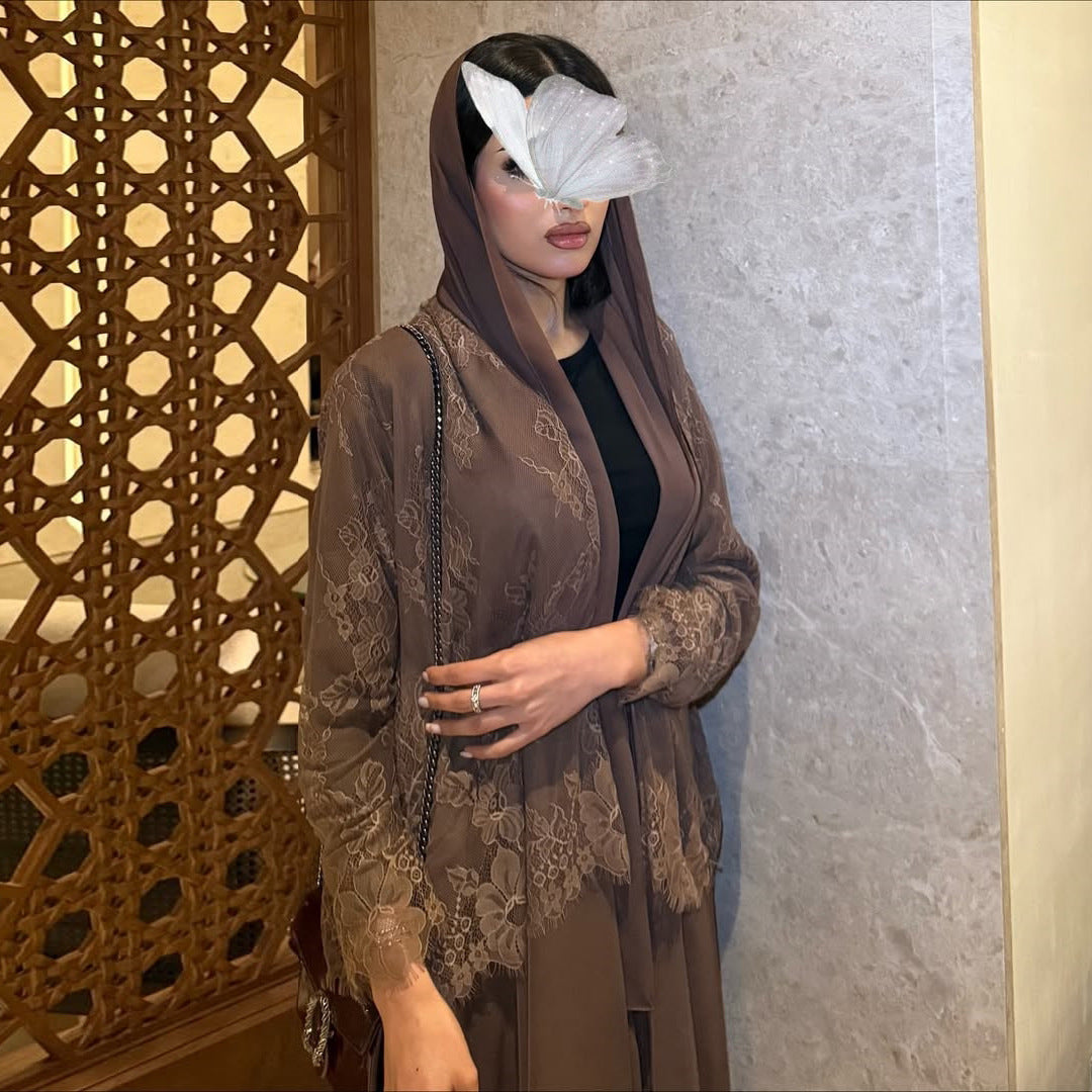 Woman wearing a brown lace outfit with a decorative wall in the background