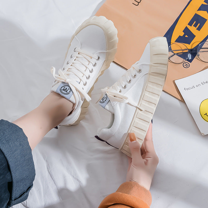 White sneakers with beige soles held by a person on a light background