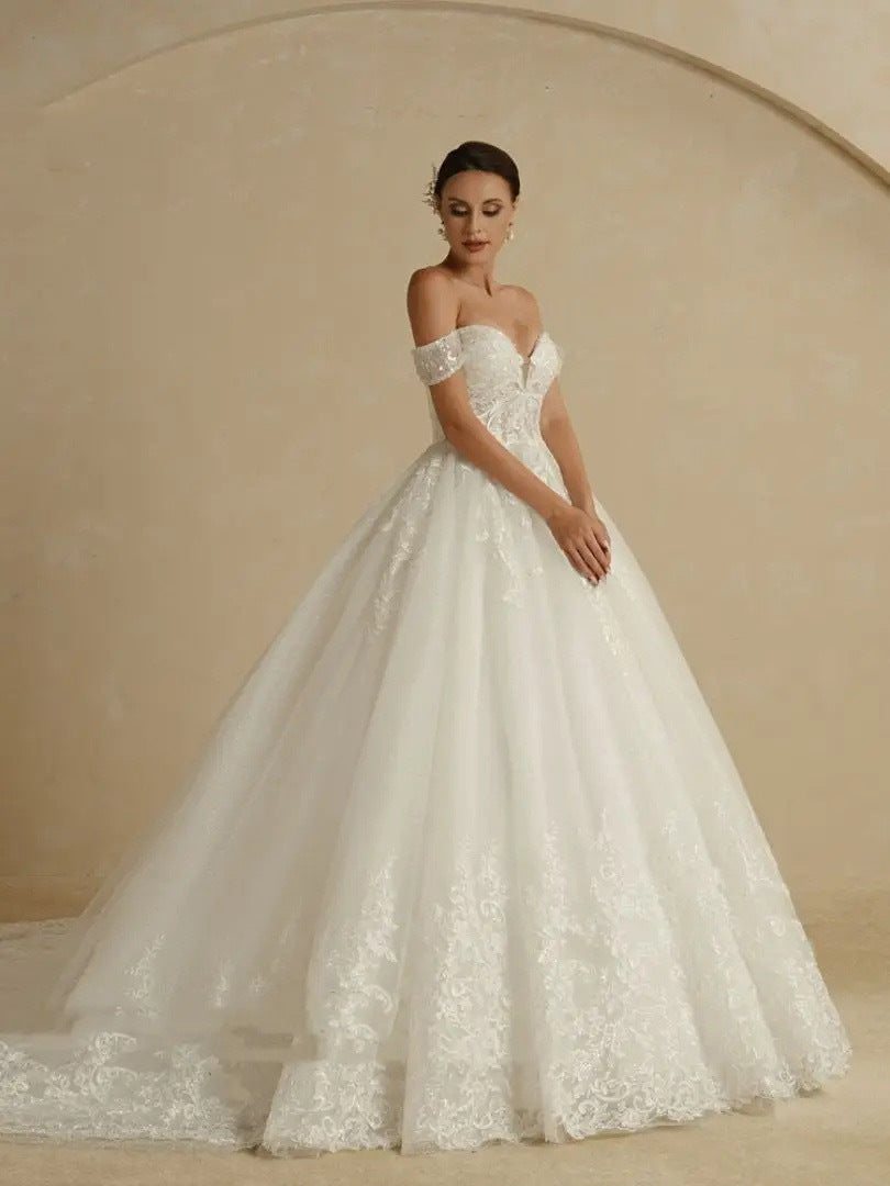 Woman wearing a white lace wedding dress against a beige background
