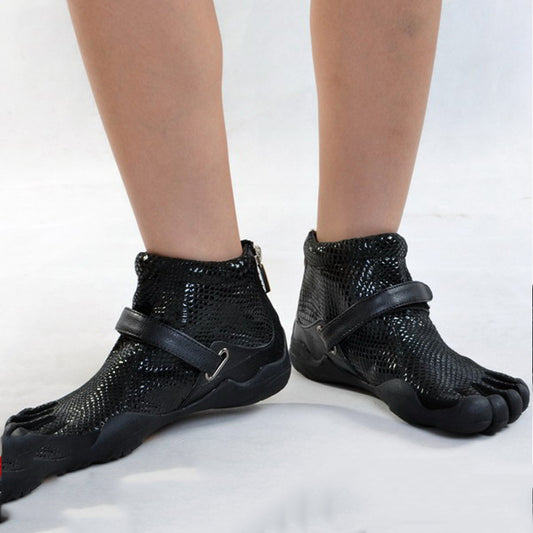 Black open-toe shoes with straps worn by a person on a white background