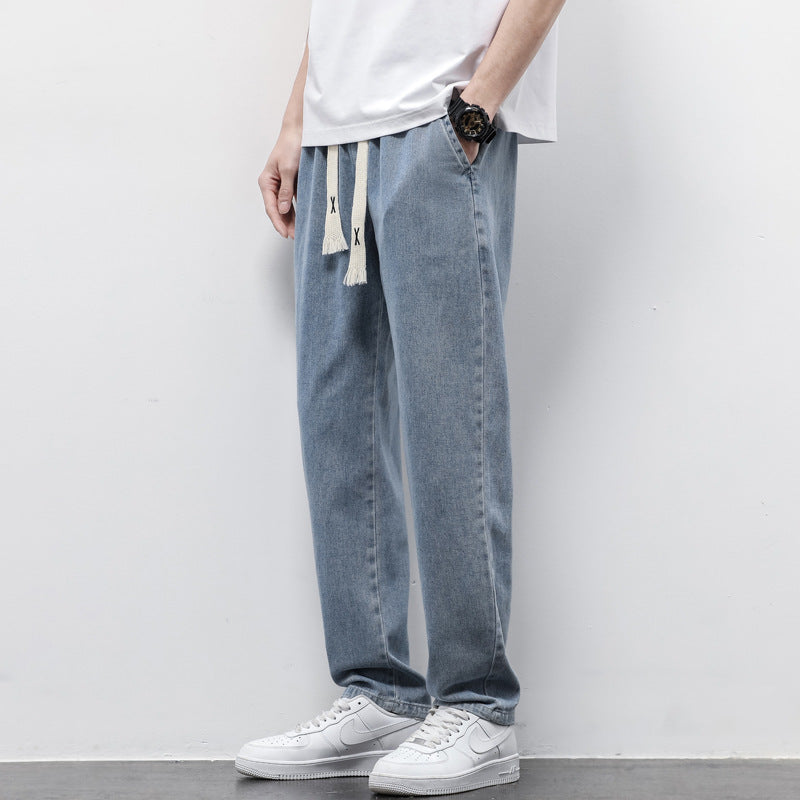 Person wearing light blue jeans and white sneakers against a plain background