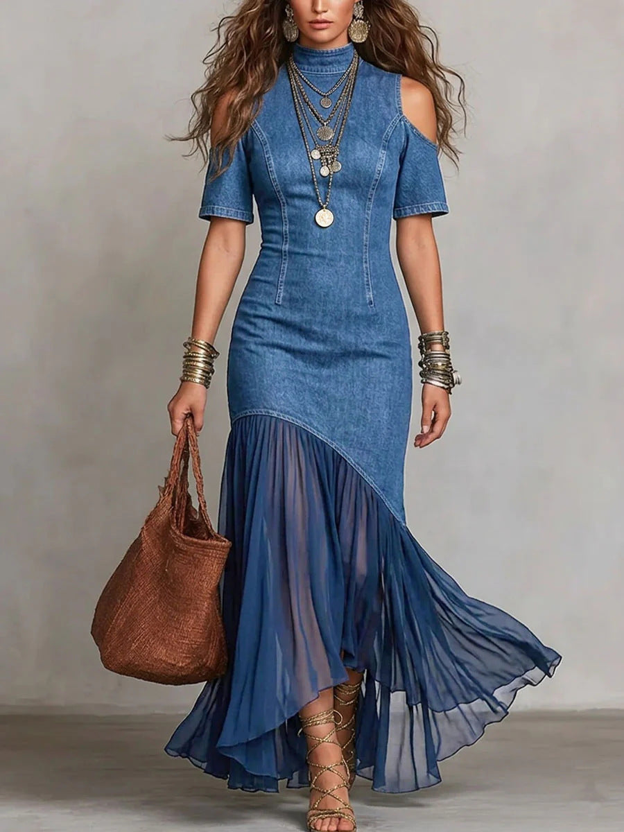 Woman wearing a blue denim dress with sheer overlay holding a brown handbag against a plain background by millivan