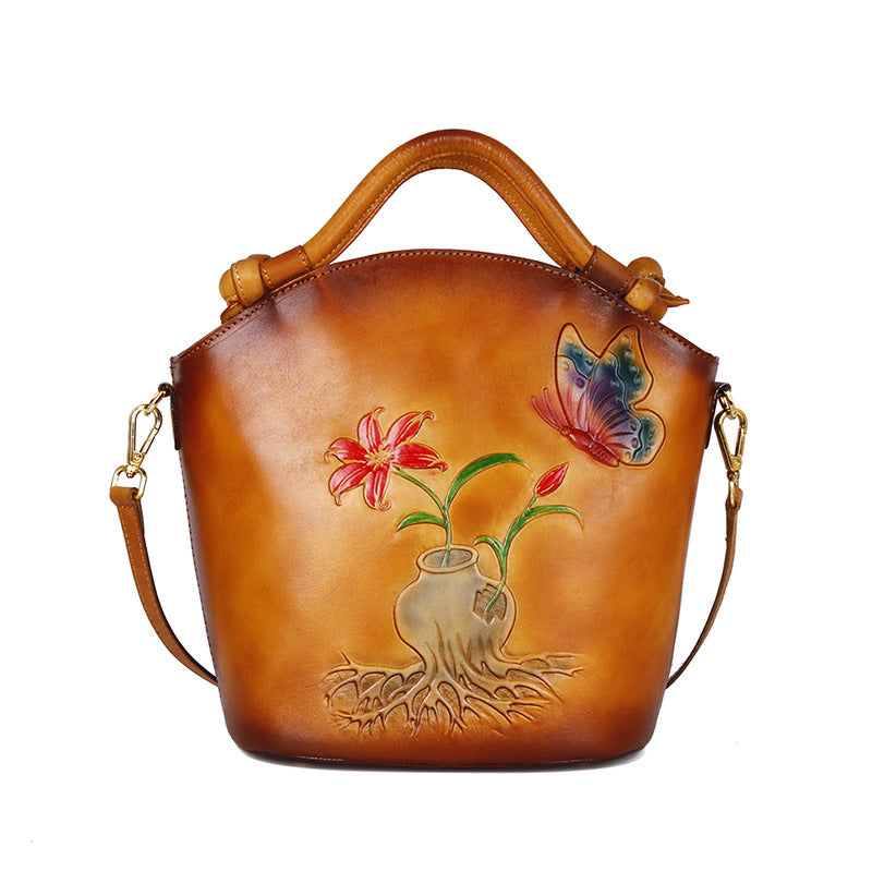 Brown leather handbag with floral and butterfly design on a white background
