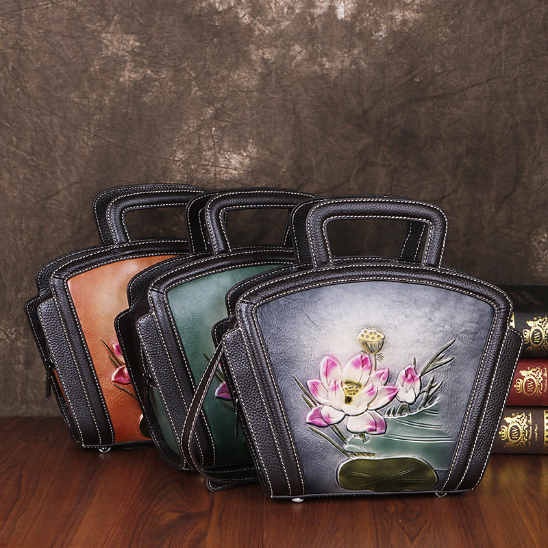 Set of leather-bound books with floral designs on a wooden surface and brown textured background