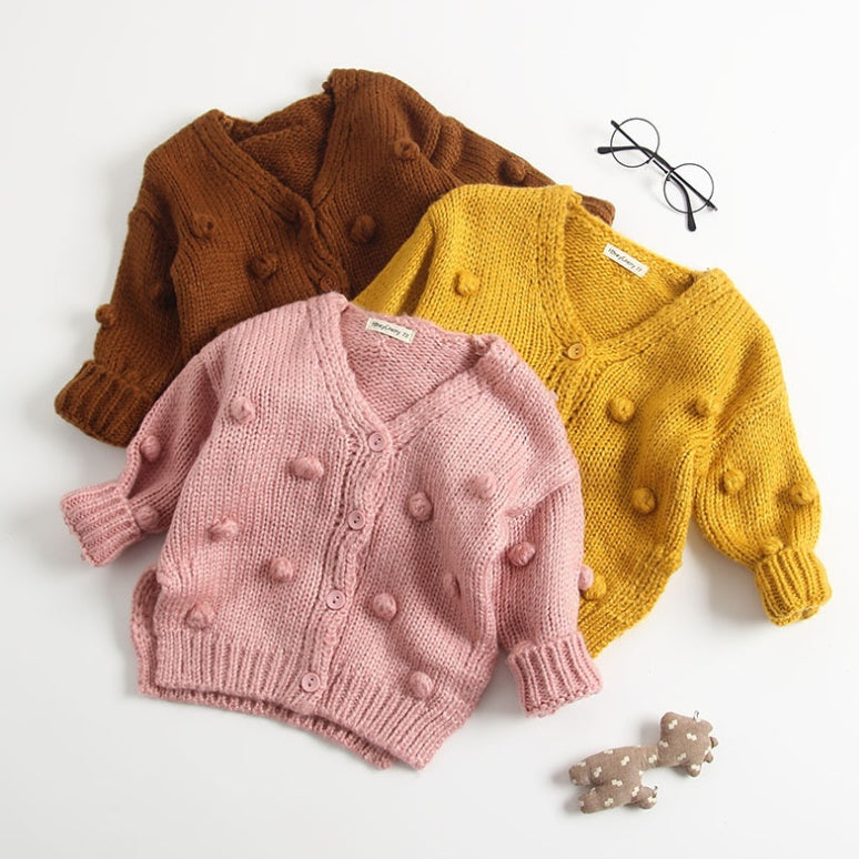 Three children's cardigans in brown, pink, and yellow on a white background.