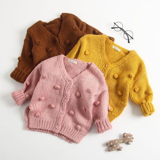Three children's cardigans in brown, pink, and yellow on a white background.