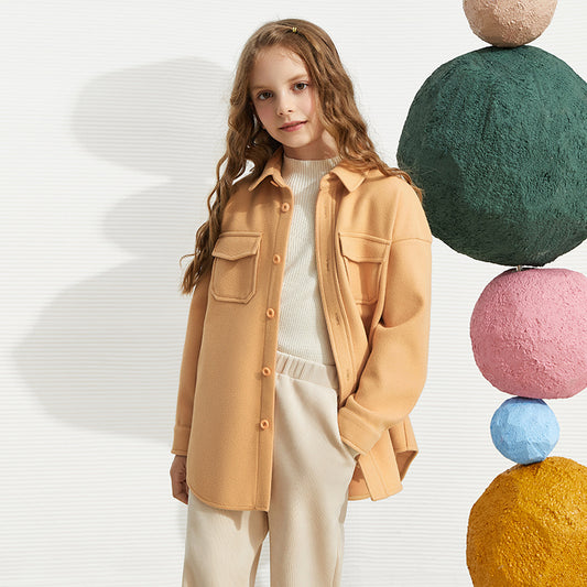 Woman wearing a beige jacket with colorful spherical objects in the background