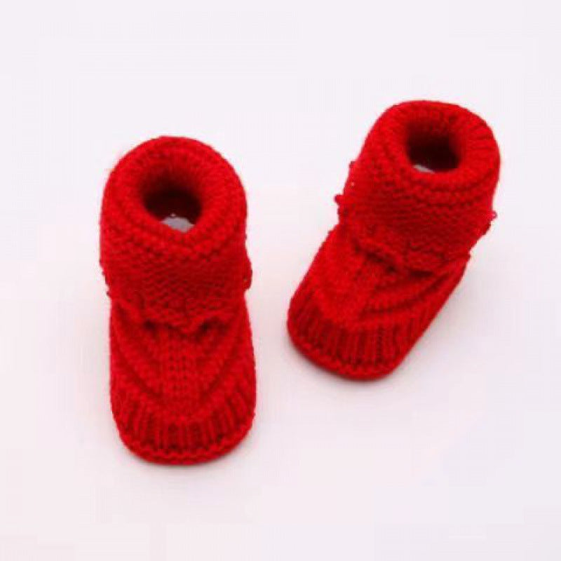 Pair of red knitted baby booties on a white background