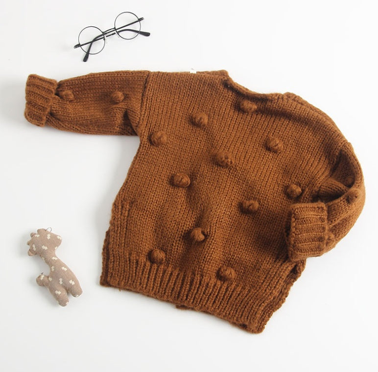 Brown knitted sweater with pom-poms on a white background