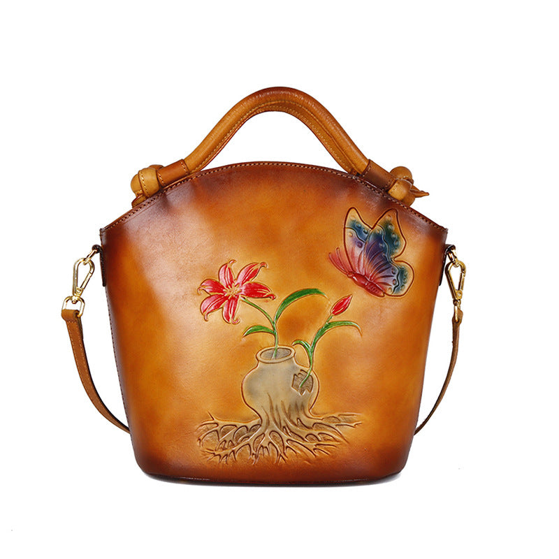 Brown leather handbag with floral and butterfly design on a white background