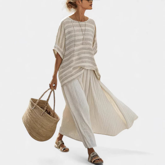 Woman wearing a beige and white striped dress holding a woven bag on a white background