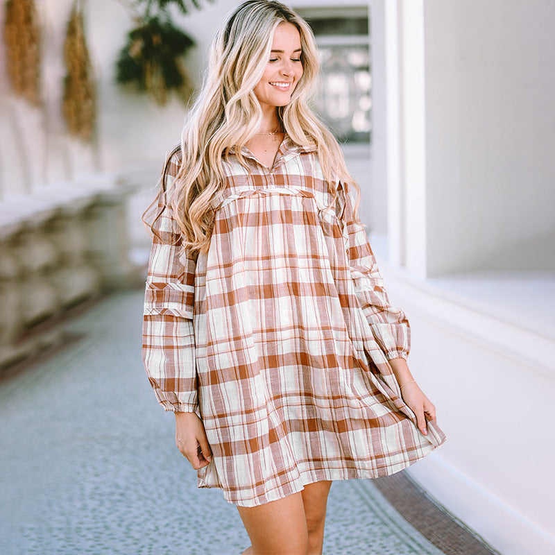 Woman wearing a plaid dress standing indoors with a blurred background