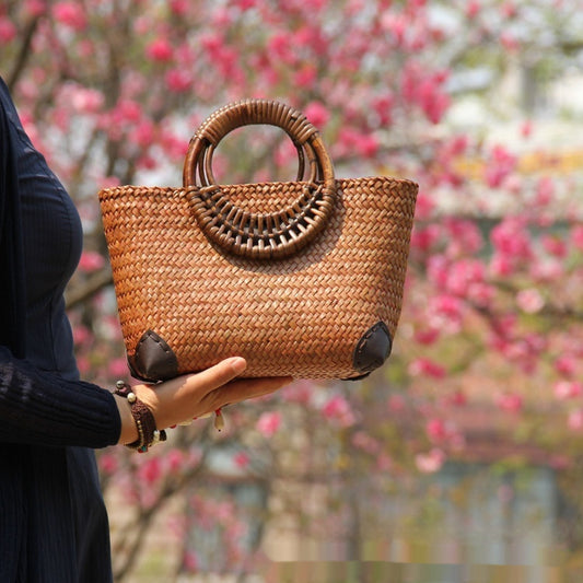 Person holding a woven handbag with floral background