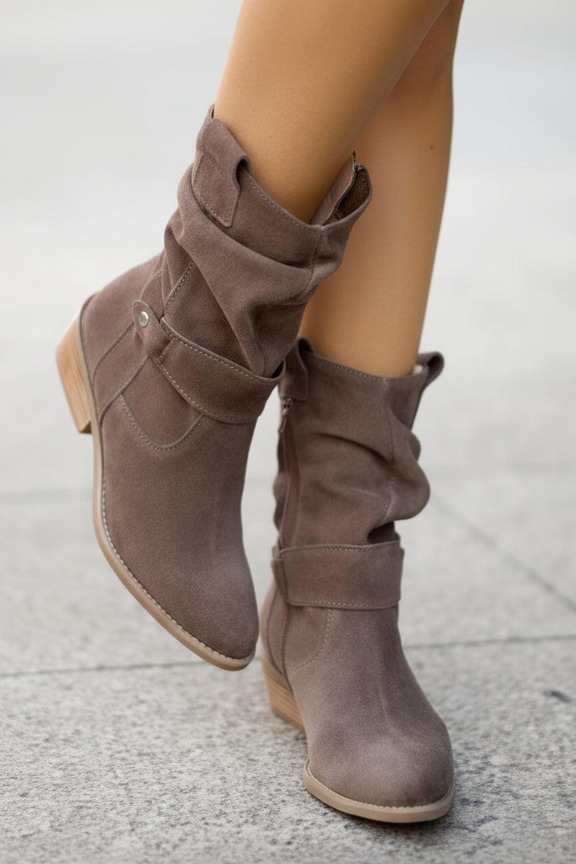 Brown knee-high boots worn by a person on a light gray pavement.