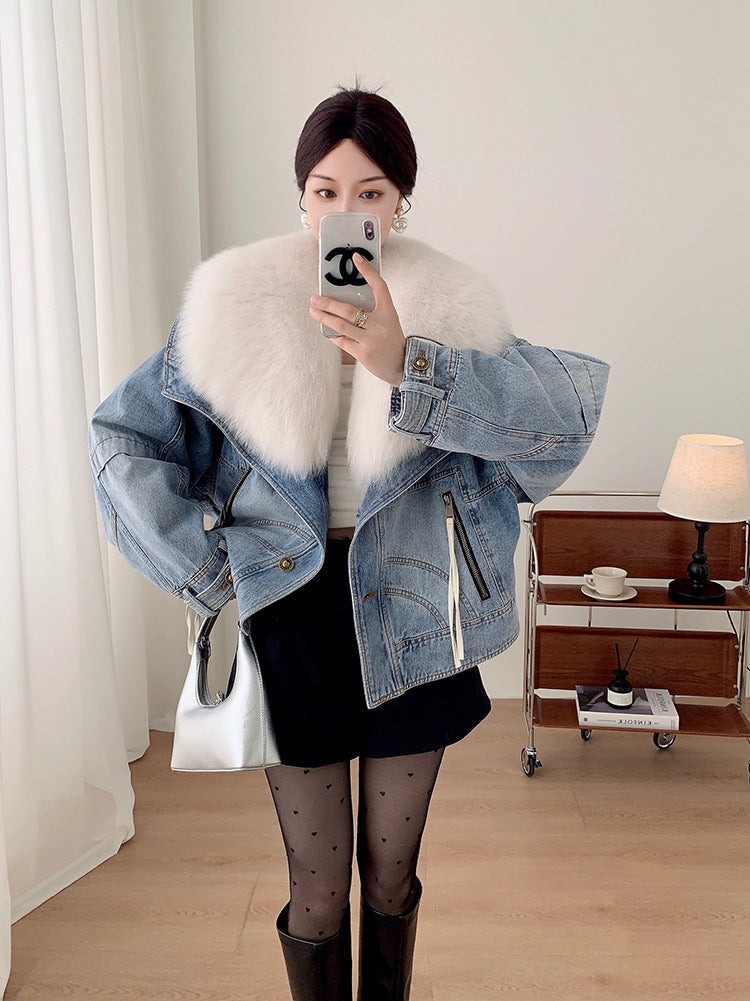 Person wearing a denim jacket with fur collar in a room.