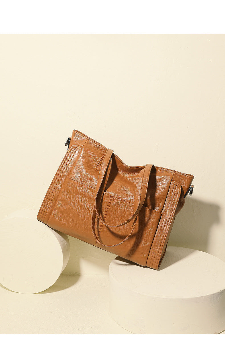 Brown leather tote bag on a beige background