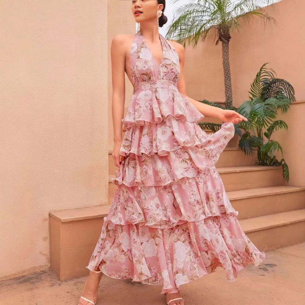 Woman in a pink floral dress standing outdoors with plants in the background