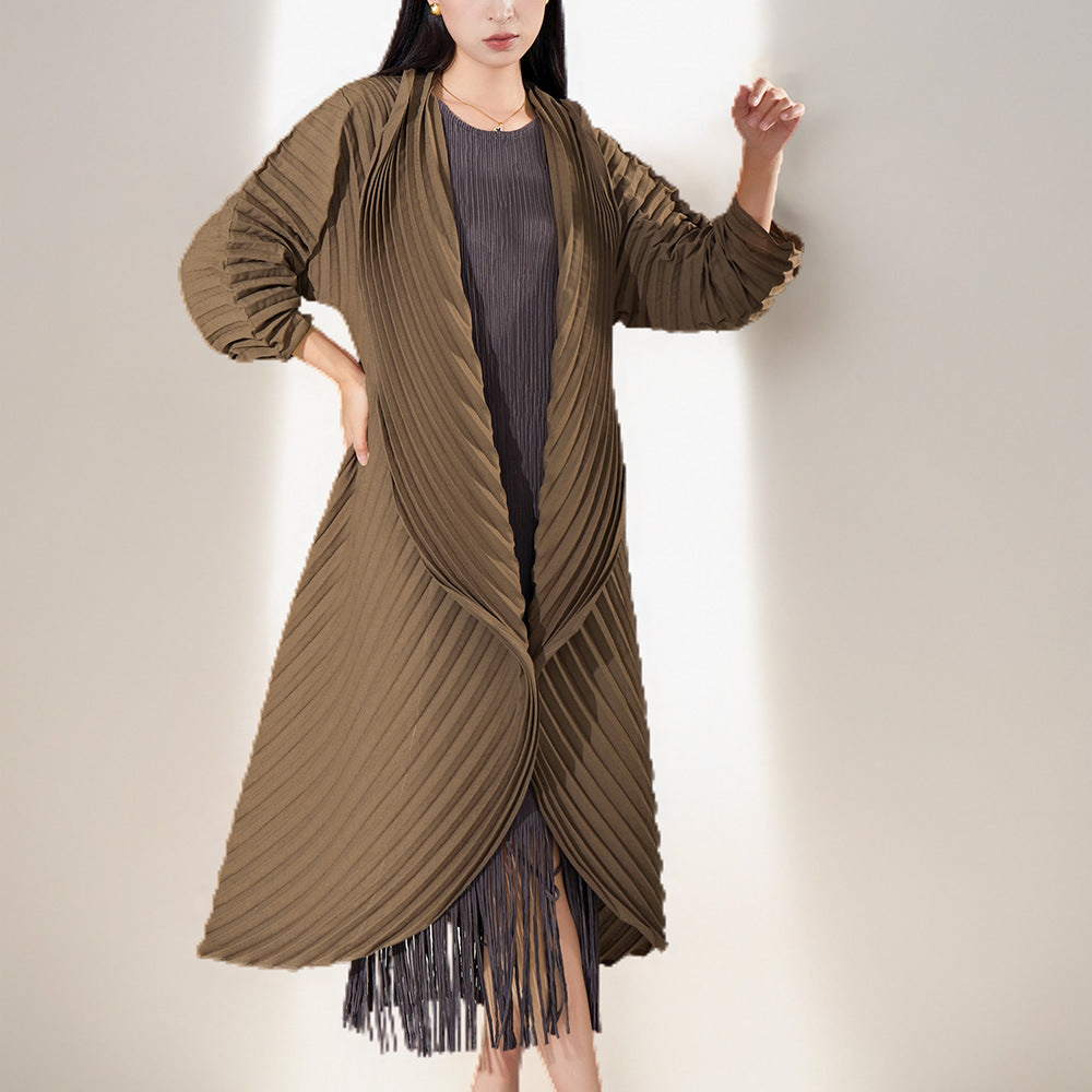 Woman wearing a long brown pleated coat with fringe details on a plain background