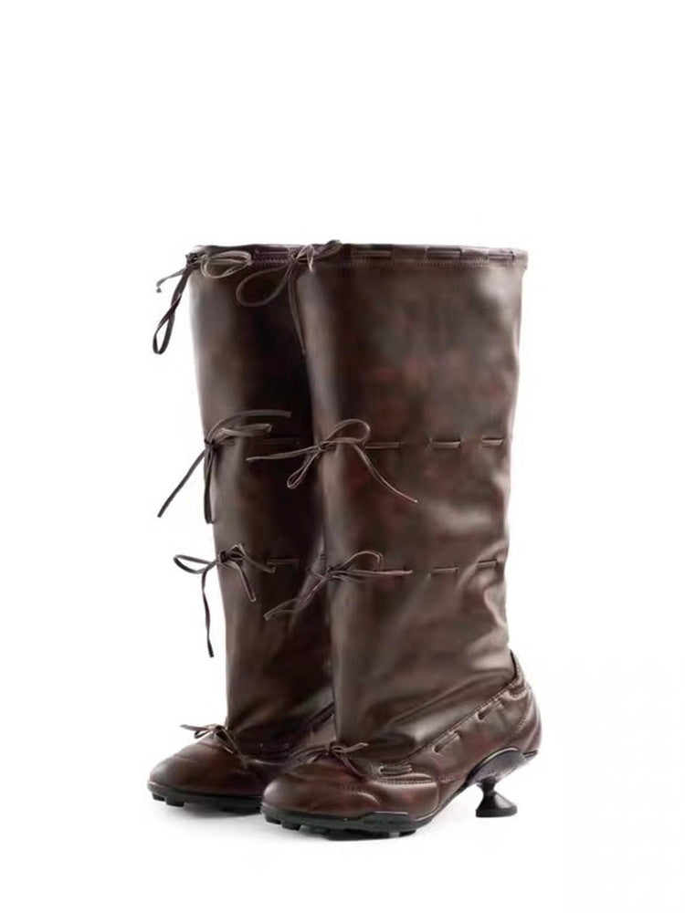 Pair of brown leather knee-high boots with laces on a white background