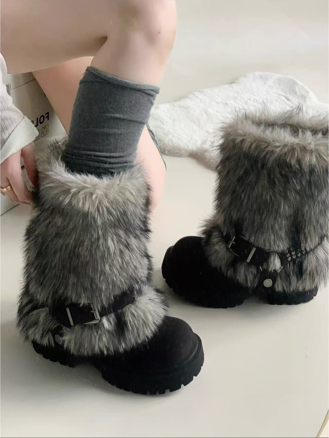 Gray fuzzy slippers with black soles on a light background