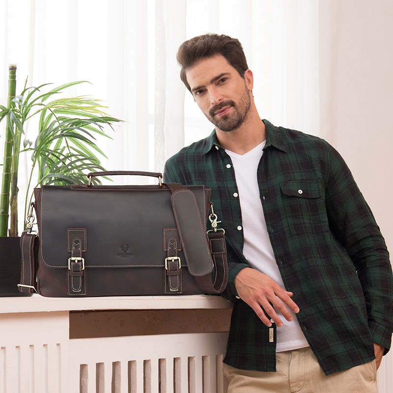 Man in plaid shirt with brown leather satchel on white surface